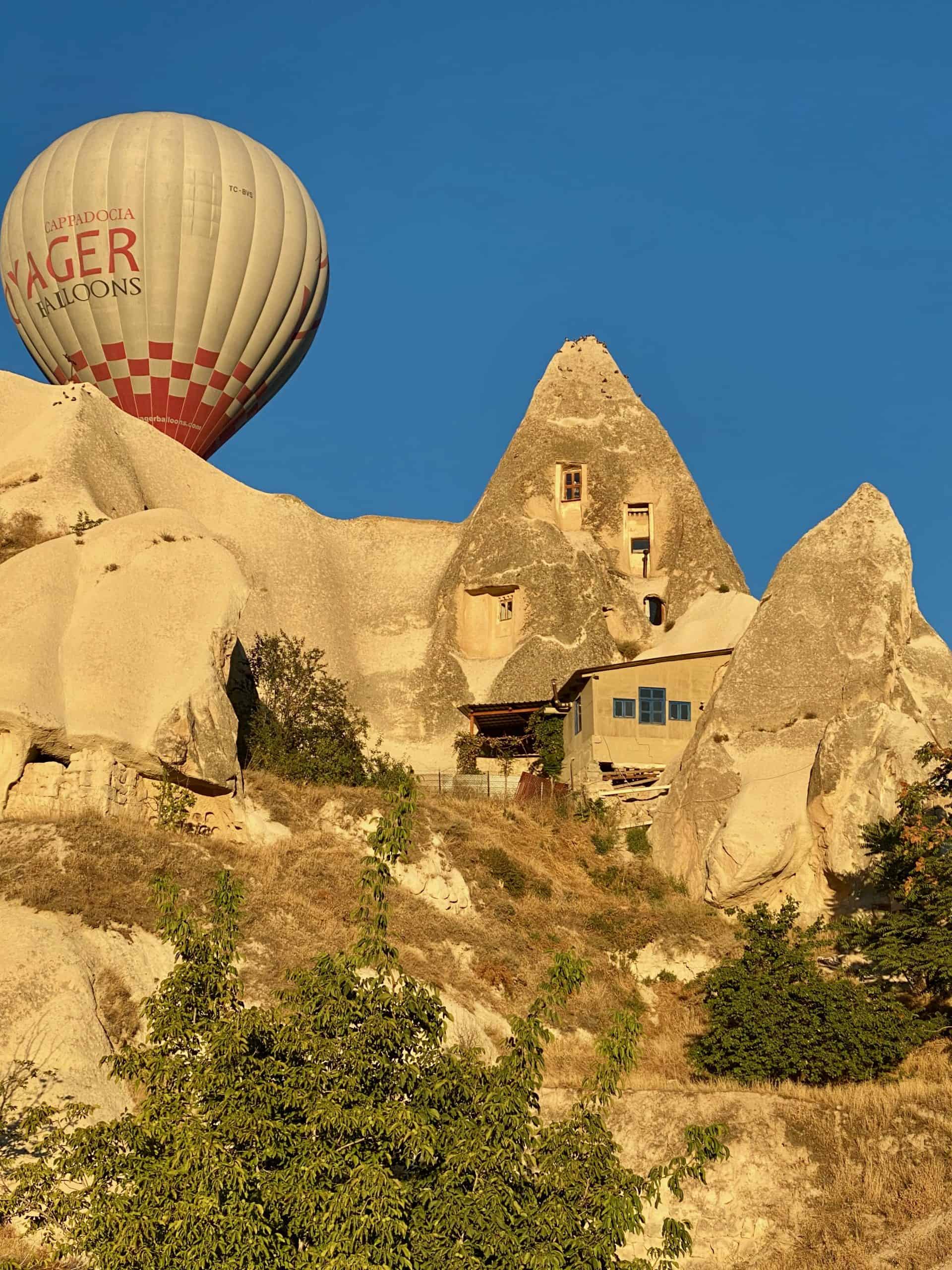 Hot air balloon rising behind rock formations in Göreme