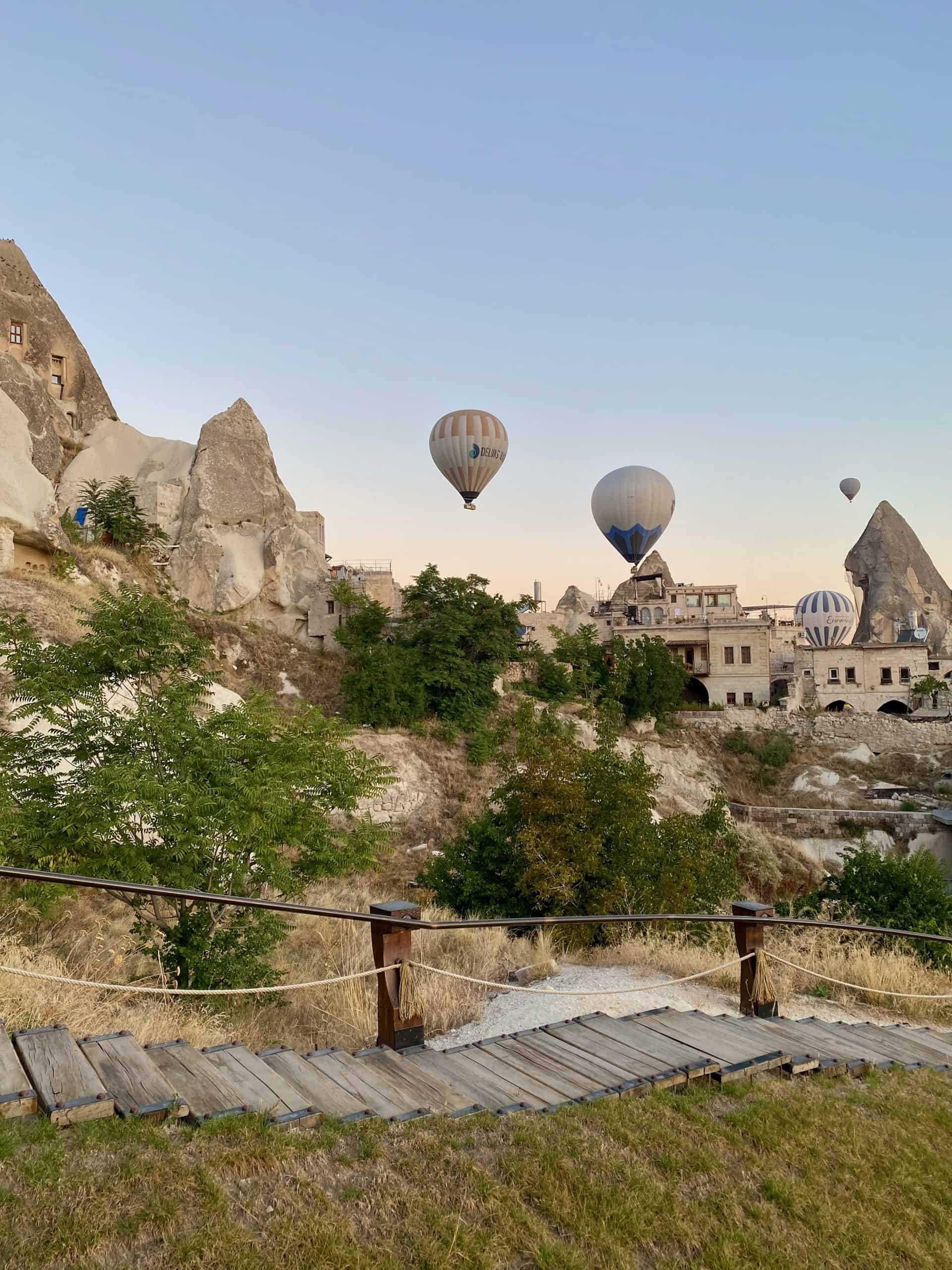 View of Goreme valley and hot air balloons from a cave hotel terrace.