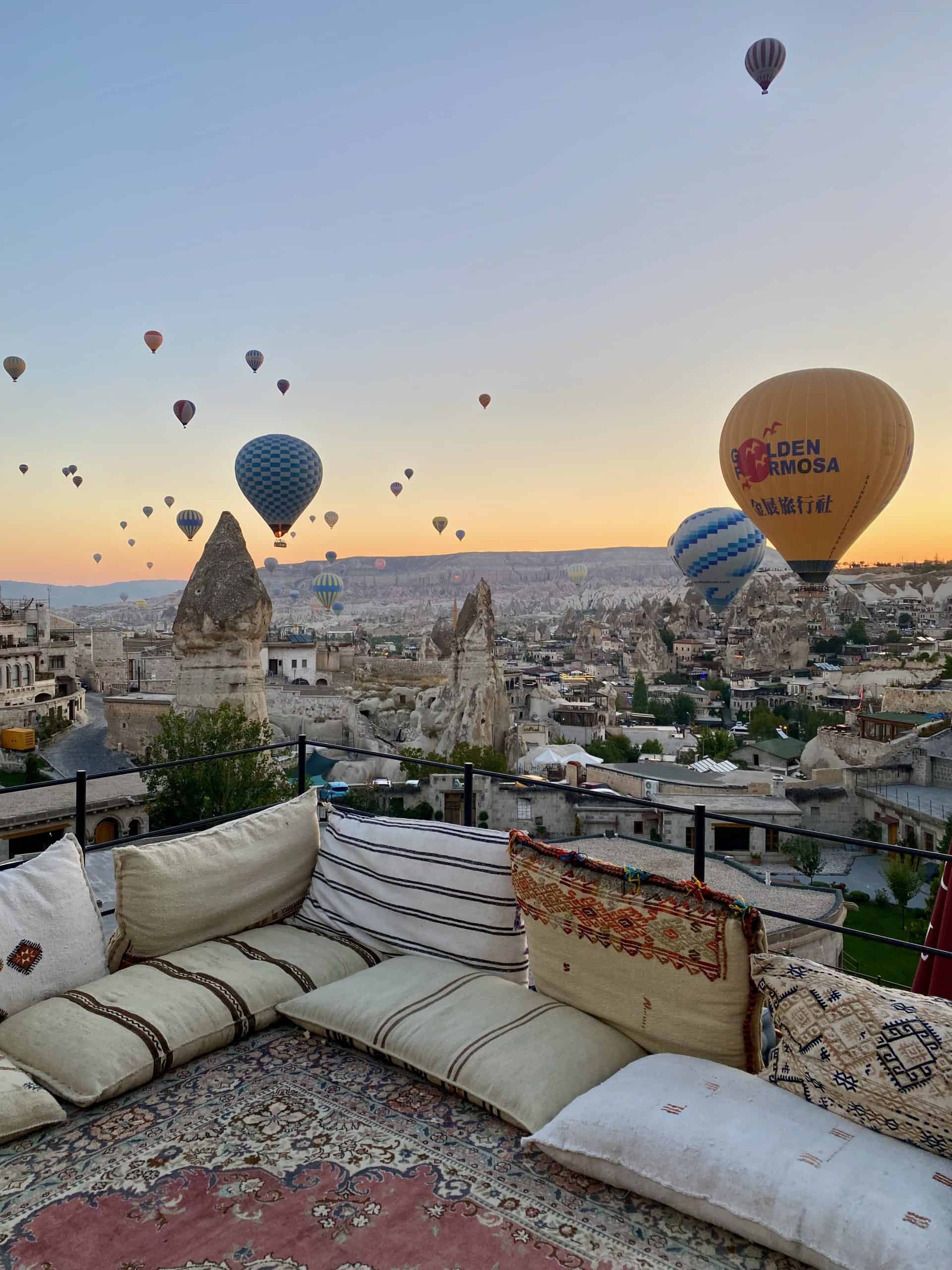 View of Goreme valley and hot air balloons from a cave hotel terrace.
